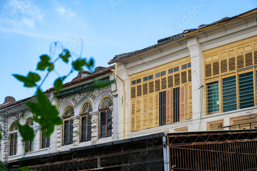 Street view of a row of colorful colonial era shophouses facade in George Town, Penang, Malaysia. The heritage architecture reflects the multicultural history of this UNESCO world heritage site.