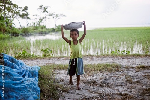 Underaged boy is carrying weights on his head, child labour  in third world country 