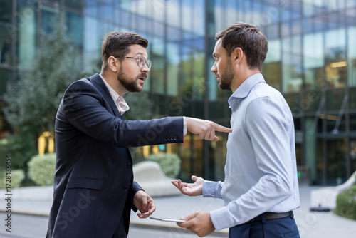 Bild auf Leinwand Two angry businessmen are having a tense argument, one pointing a finger while t