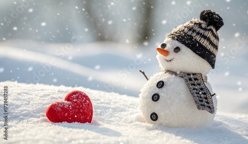 This is a photograph of a snowman standing in a snowy landscape. The snowman, made from three large snowballs stacked, has a black and white knitted hat with a pom-pom, a carrot nose, coal eyes and mo