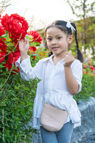 The girl stands to take pictures in the flower garden.