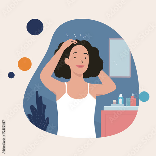 A woman is grooming her curly hair while standing in a bathroom. The space features a mirror and various hair products on the counter, creating a cozy atmosphere.