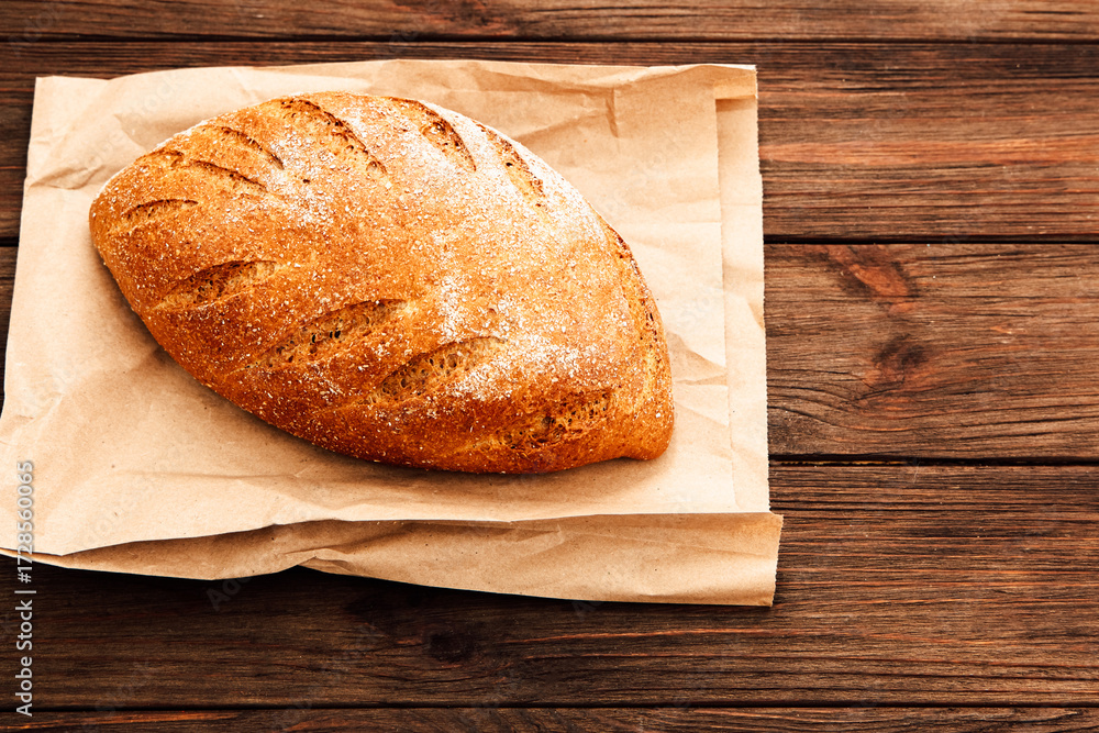 Naklejka premium Freshly baked artisan bread on rustic wooden surface in cozy kitchen setting