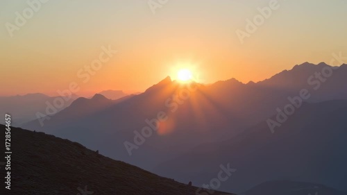 Golden Sunrise over Mountain Peaks with Sun Rays and Haze.