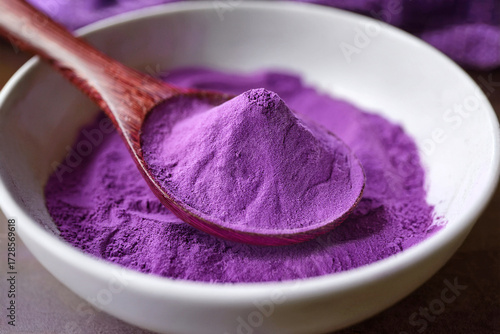 Close-up of purple sweet potato powder, also known as ube powder,  on a brown wooden spoon in white Japanese-style bowl. Bright and soft natural lighting.  Generated image