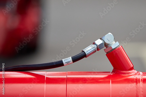 Close-up of two hydraulic hose fittings attached to a red industrial machine