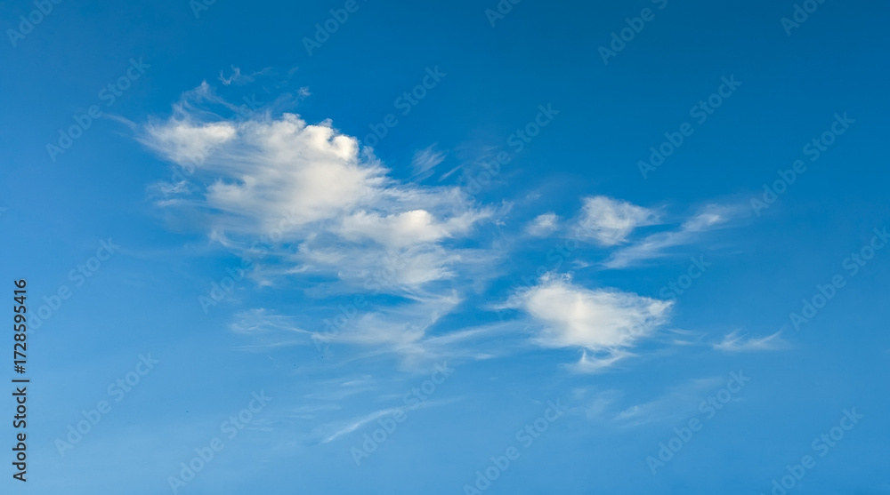 Obraz premium Blue sky with cloud. Mixed cumulus and cirrus clouds are scattered by the wind across the vast sky on light background.
