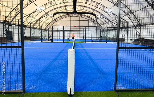 empty paddle tennis court with lights on in a covered shed 