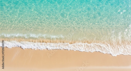Aerial view of a serene beach with gentle waves and sandy shoreline in soft teal and sand tones