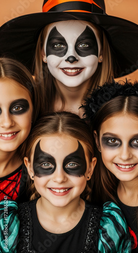 Close-up of four girls in Halloween costumes, showcasing creative face paint designs, capturing the spirit of fun and festivity