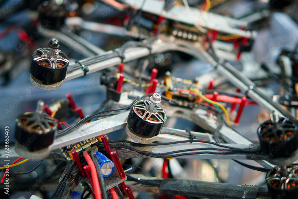 Fototapeta premium Close-up view of dismantled quadcopter motors, wires, and circuit boards, illustrating repair, recycling, or drone production process. Photo