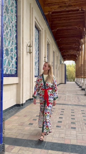 Woman in traditional Uzbek patterned outfit walking by memorial complex in Tashkent