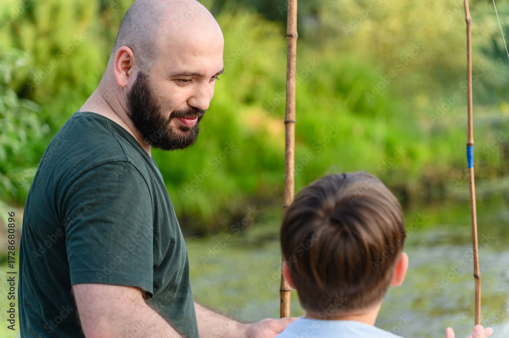 Obraz premium Father and son fishing together by calm river.