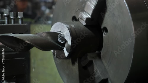 Close-up metal shavings which cutting off drilling detail on lathe machine. Metalworking metallurgical industry, automated machinery production manufacturing. Process of creating new metal parts.