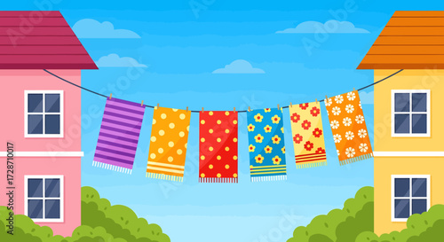 Colorful patterned towels hanging on a clothesline strung between two houses under a bright blue sky.