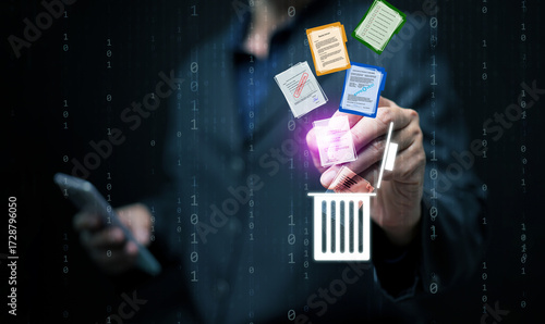 Businessman using smartphone and hologram interface to delete digital documents into recycle bin, symbolizing secure file management, data cleanup, and cybersecurity concept.