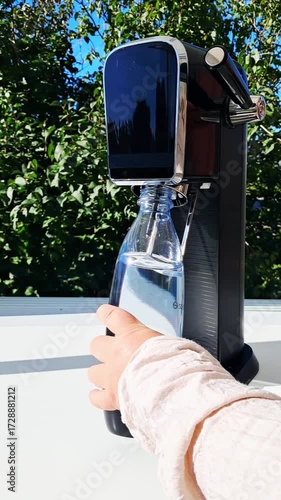 Soda making machine at home.The woman inserts the bottle into the device.