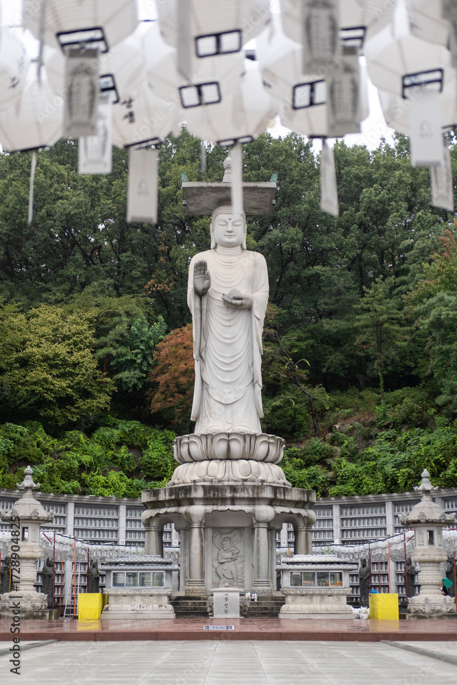 Fototapeta premium Mireuk Daebul statue of the bodhisattva Maitreya at Bongeunsa Temple, a Buddhist temple in Seoul. With background of autumn leaves. It is the tallest stone statue in Korea.