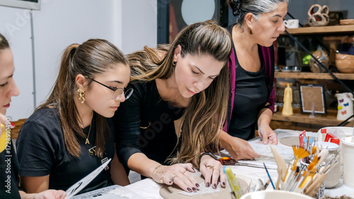 During an art event in a studio, middle age woman is painting Christmas ornament shapes she crafted on clay
