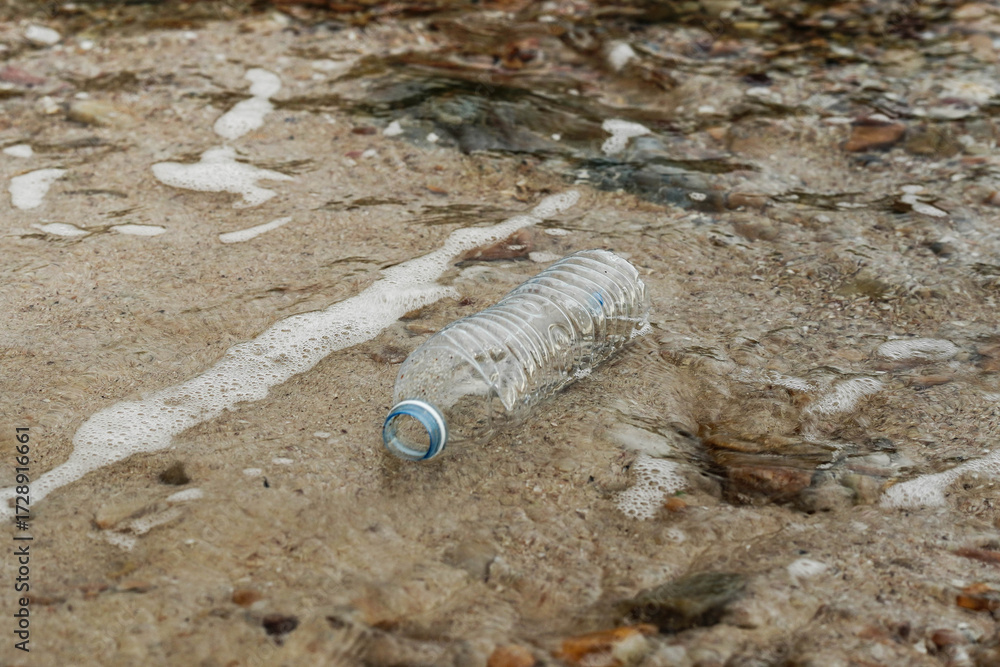 Obraz premium Plastic bottle on sandy beach pollution.