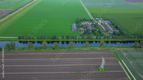 Aerial view of farmland with farm buildings next to water canal in Netherlands. Rural landscape.