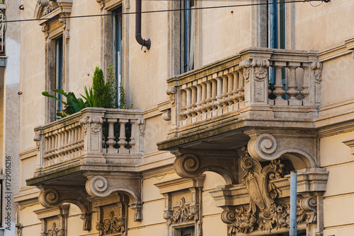 Fototapeta Stone balconies with classic columns on historic Milan building facade