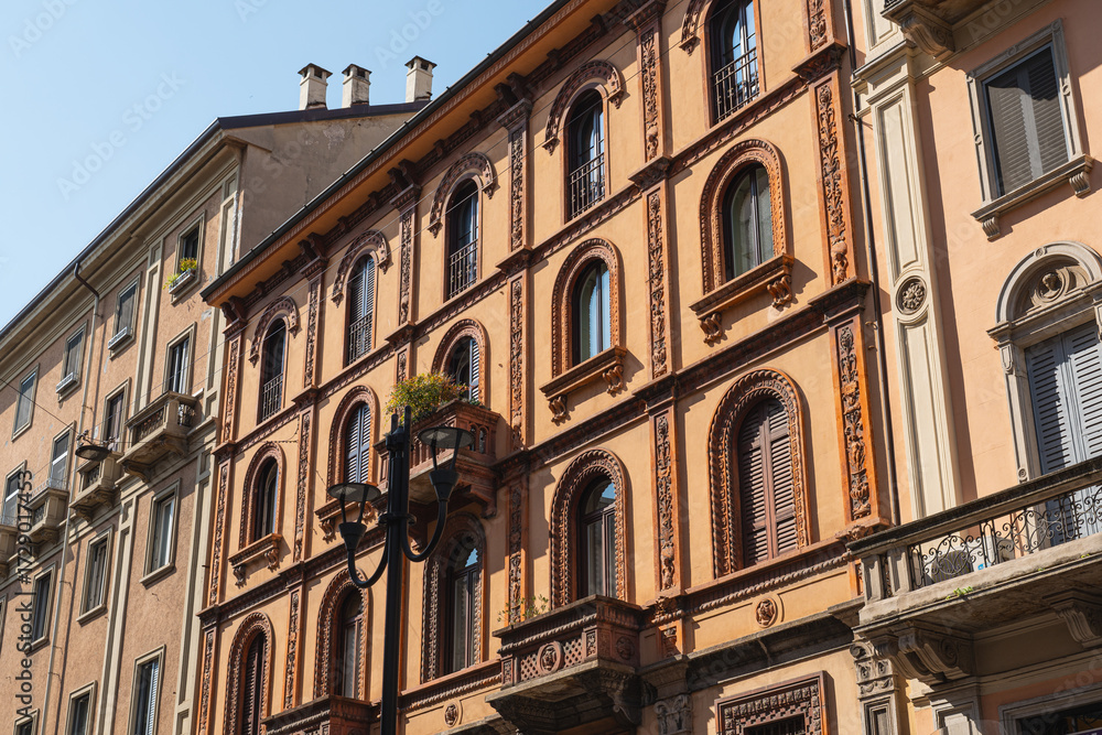 Fototapeta premium Ornate historic orange building facade with arched windows in Milan