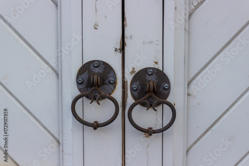 Fotografie Close-up of pair of symmetry old rusty metal hanging ring door knobs covered on