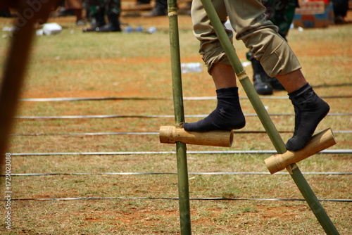 Person walking on bamboo stilts during traditional outdoor game competition, showcasing balance and skill in a cultural event.