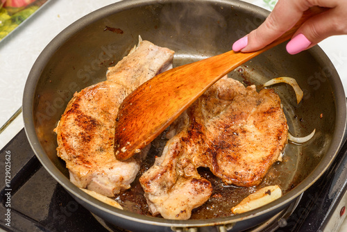 Pressing meat with a wooden kitchen spatula while frying.