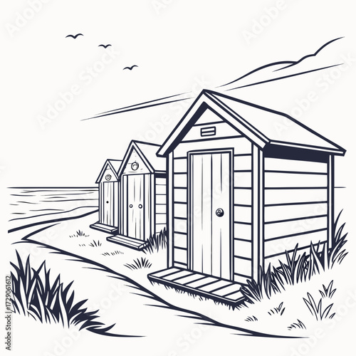 Row of simple beach huts on a sandy shore with grass and birds flying overhead
