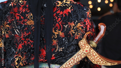 Fotografie Man presents traditional keris dagger during cultural ceremony in Indonesia, showcasing heritage and artistry with reverence