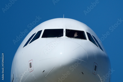 Clear Blue Sky and Aircraft Nose. Close-Up of Passenger Jet Nose and Cockpit Windows. 