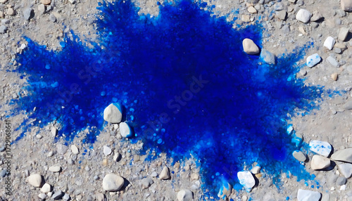 Vivid blue liquid spill absorbed into coarse gravel and earthy ground, creating an abstract vibrant splash pattern