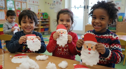 明るい光が差し込む暖かな教室で 満面の笑顔の子供たちが心を込めて作った可愛らしいサンタクロースの工作を誇らしく見せびらかすクリスマスの喜び溢れる光景. AI Generated
