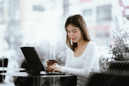 Young woman holding credit card and smartphone, making online payment while using laptop in modern cafe. Free Download Young woman holding credit card and smartphone, making online payment while using laptop in modern cafe. - GFXLoad