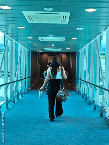 Passenger Walking Through Modern Airport Jet Bridge towards Aircraft