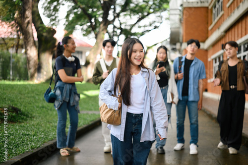 Happy young university student woman walking confidently with friends in the background, expressing freedom, identity, and self-assurance in an inclusive academic community