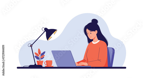 A young woman sits at a desk working on her laptop with a lamp and a potted plant.