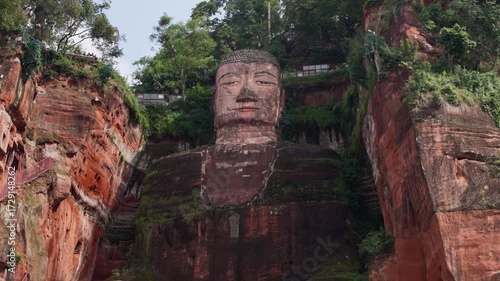 Cinematic slow motion tilt from feet to face of Leshan Giant Buddha, capturing full vertical scale and intricate cliff carving