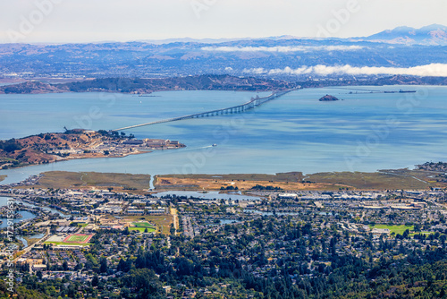 Panoramic view from Mount Tamalpais East Peak overlooking San Francisco Bay, Richmond San Rafael Bridge, Angel Island, and rolling hills of Marin County under fog and blue sky, California USA