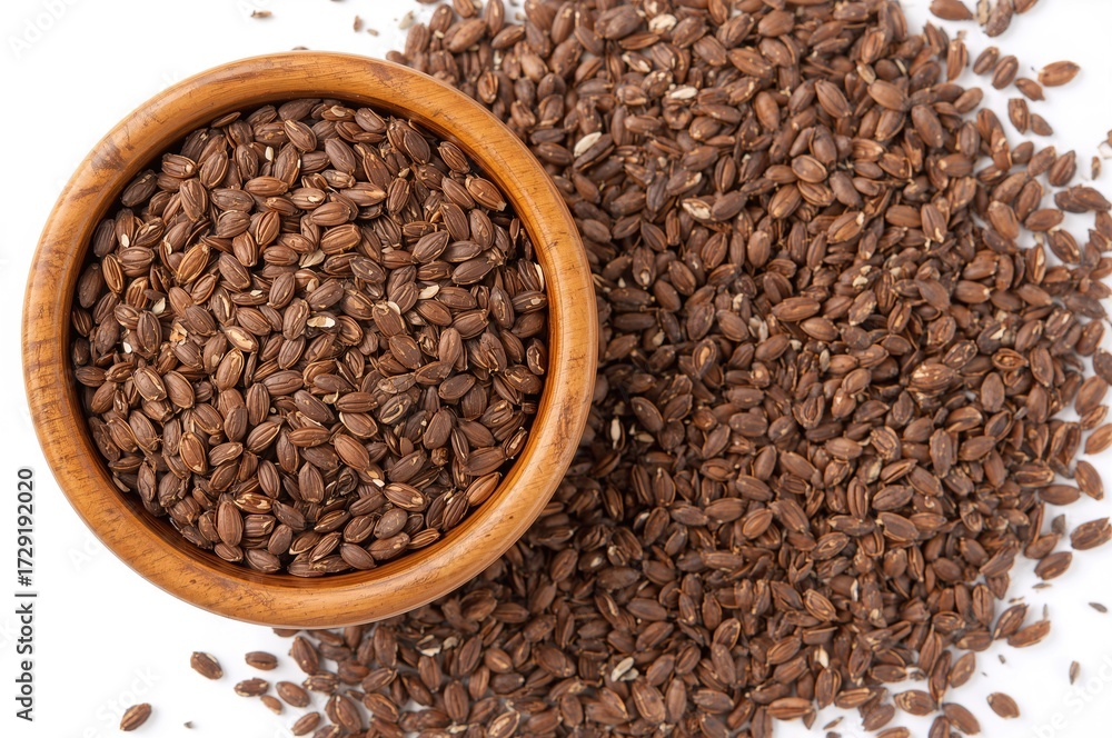 Fototapeta premium Natural wooden bowl filled with brown flax seeds with some seeds spread on a white surface