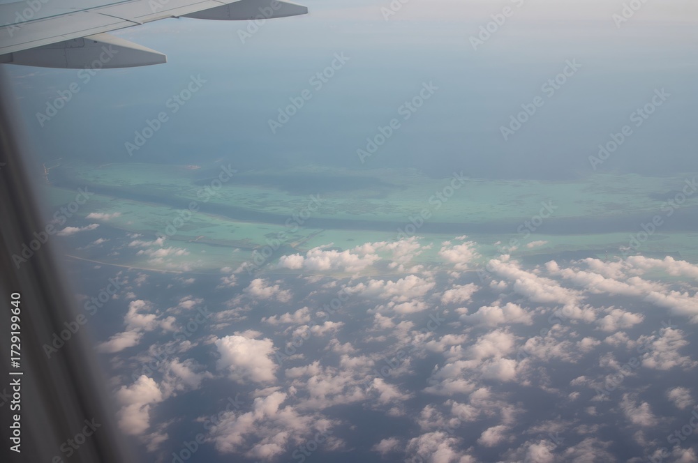 Fototapeta premium View from an airplane window showing a tropical island paradise from above, perfect for a vacation