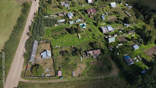 A small provincial village in the depths of the forest, with green fields in the background, filmed from above by a drone.