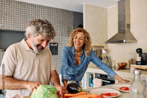 Obraz na płótnie Portrait of happy senior mid aged mature couple prepering meal with fresh vegate
