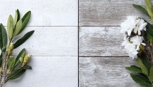 Fresh green leaves and delicate white flowers arranged on a light gray wooden surface, creating a serene and natural aesthetic.