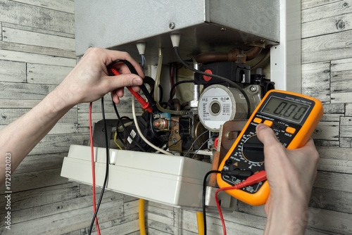 A young man is repairing an electric water heating boiler.