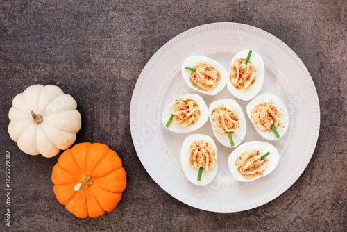 Autumn pumpkin theme deviled eggs. Top down view table scene on a dark background. Fall breakfast concept.
