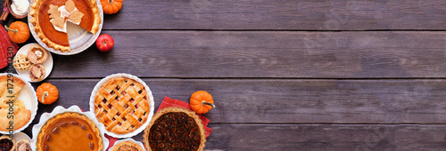 Homemade autumn pie corner border. Top down view on a dark wood banner background with copy space. Variety of apple, pumpkin and pecan pies.