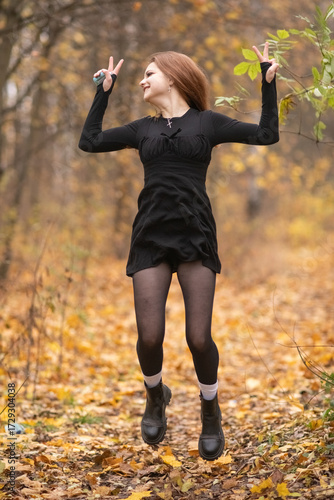 Young woman with long hair twirling in a forest during autumn, surrounded by colorful leaves, showcasing a joyful and carefree spirit in a natural setting